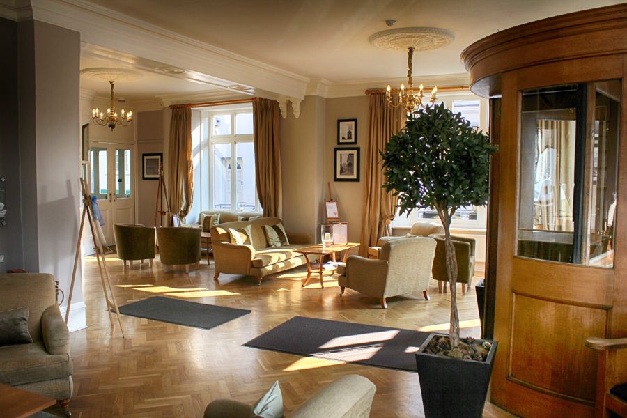 The hotel lobby of The Bell in Sandwich with wooden floors and armchairs.