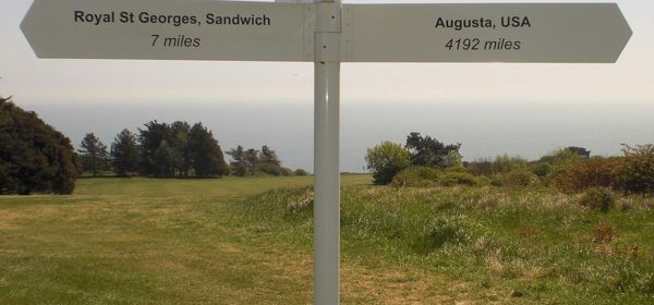 A white signpost to Royal St George's at Sandwich and Augusta, USA on the golf course at Walmer and Kingsdown Golf Club.