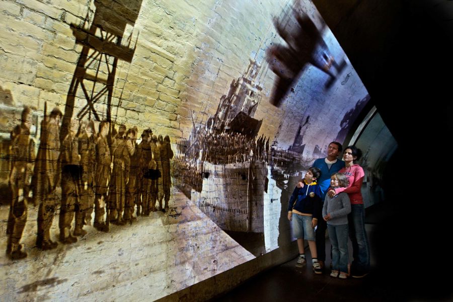 A family of four looking at film footage of Operation Dynamo projected onto a tunnel wall.