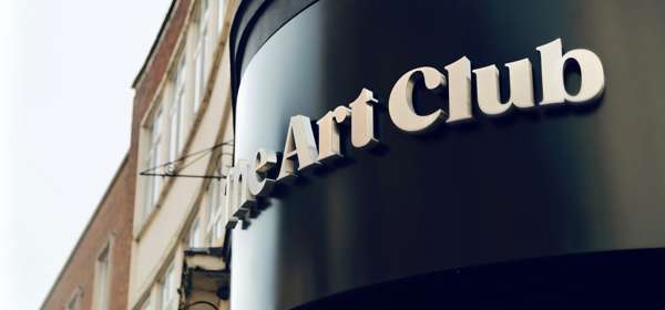 A rounded shop sign, The Art Club in white text on black