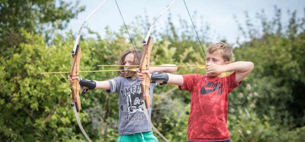 Two children doing archery target practice