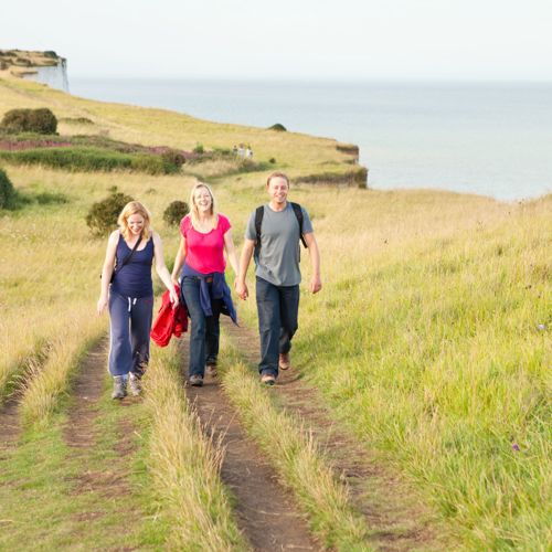 Three people walking towards the camera on the White Cliffs of Dover.