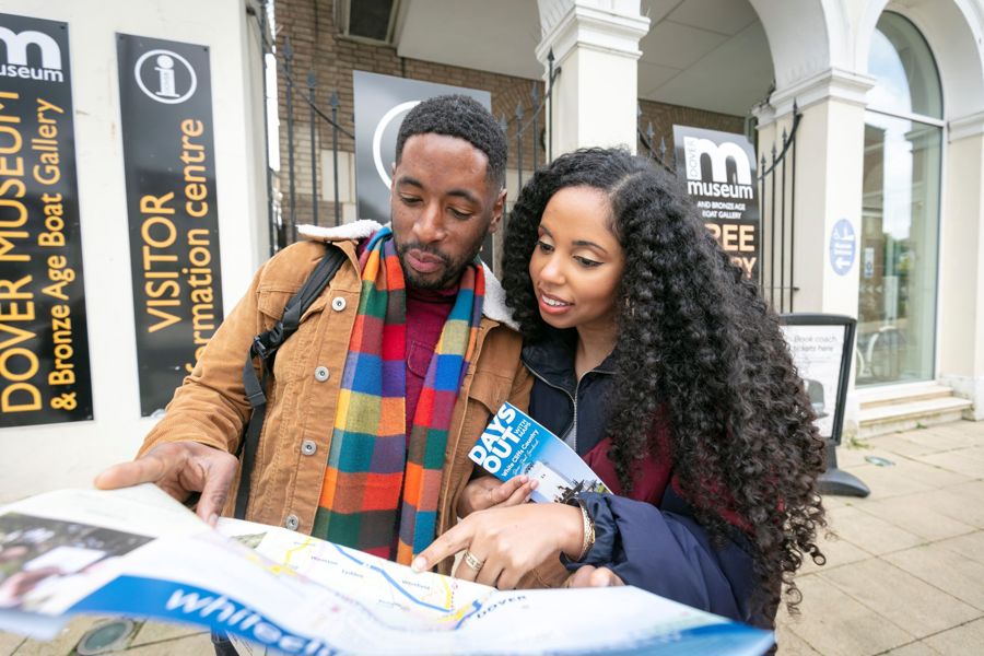 A couple standing outside a visitor information centre holding a map