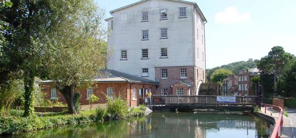 A mill with water wheel and a river in the foreground