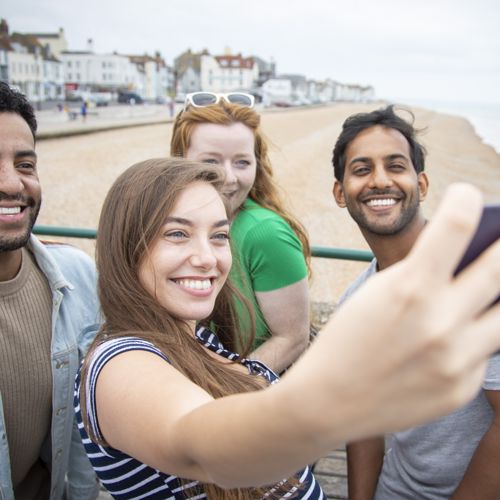 Four people taking a selfie with Deal seafront in the background.