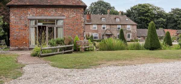 Exterior of a large old house set in garden with trees.