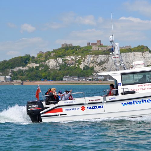 Wetwheels boat with passengers heading out of Dover Harbour with Dover Castle and the white cliffs in the background