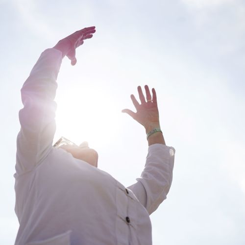 A person with their arms raised towards the sun.