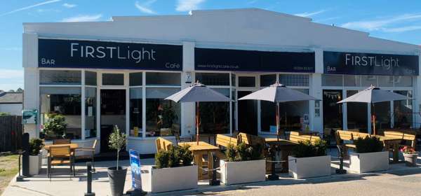 Exterior image of Firstlight Cafe Terrace with tables, chairs and umbrellas