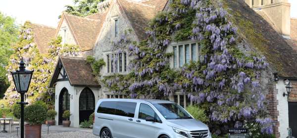 Silver Mercedes van outside wisteria-clad building