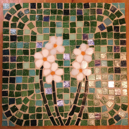 A mosaic tile made of green, white and blue pieces of ceramic forming the image of flowers.