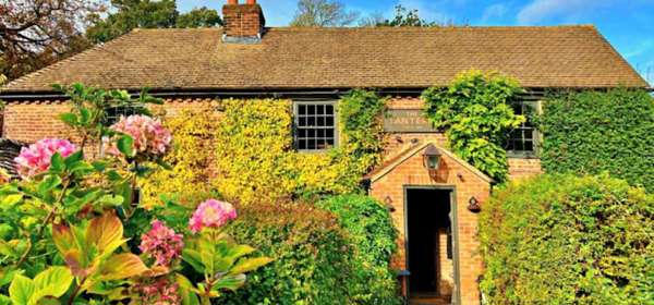 Exterior of The Lantern Inn with ivy climbing the walls and neat bushes up the pathway to the entrance.