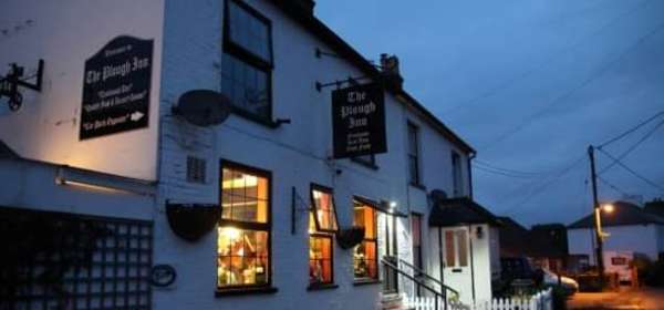 The white exterior of The Plough Inn at nightfall