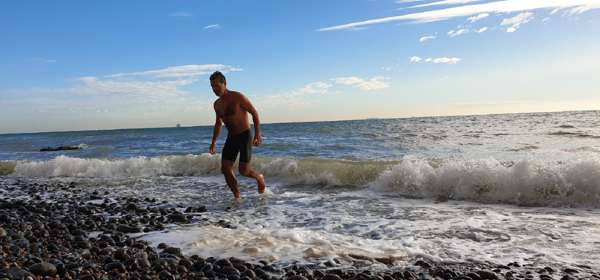 A man emerging from the sea after a swim