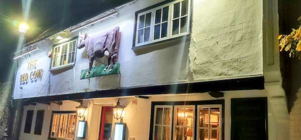 Exterior of the white washed walls of The Red Cow at night lit up