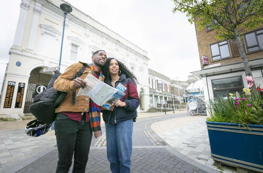 A couple holding a map with Dover Museum in the background.