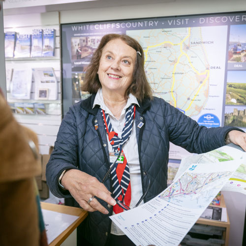 A female member of the visitor information team showing a map and guide to a visitor.