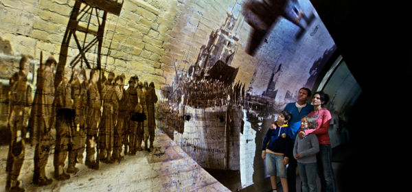 A family group looking at a projection of a World War scene onto a wartime tunnel.