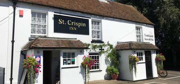 Exterior of the St Crispin Inn with whitewashed walls and colourful hanging baskets