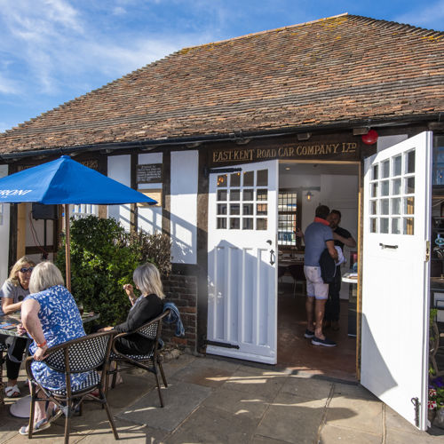 Old bus waiting room building converted to a bar with tables and chairs outside