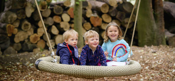 Three children in a swing at Walmer Castle Gardens play area