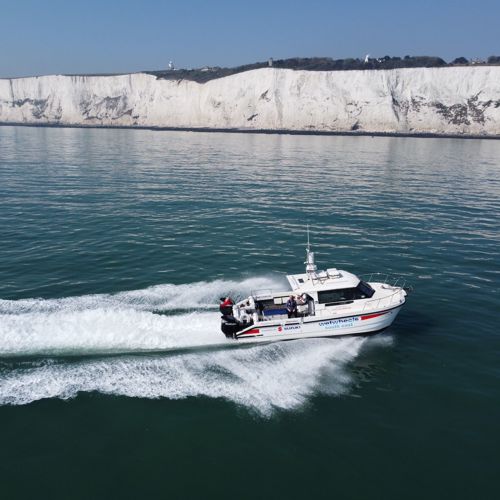 The Wetwheels South East boat speeding across a calm sea with the White Cliffs in the distance.