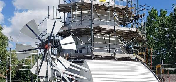 White Mill covered in scaffolding with the cap on the ground during renovations