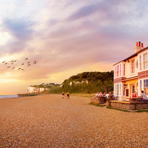 The Zetland Arms located on a pebble beach with cliffs in the background.