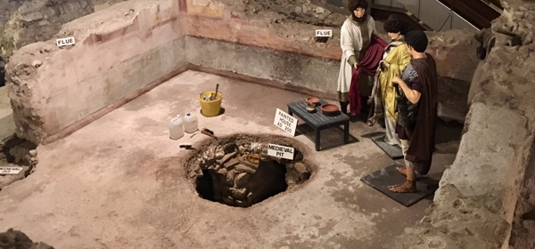 Mannequins in Roman costume stand amongst archaeological remains of the Roman Painted House